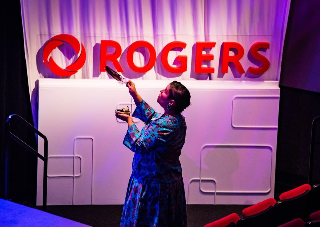 Nicole McCormick, employée de Rogers, tenant une plume à côté du logo de Rogers.