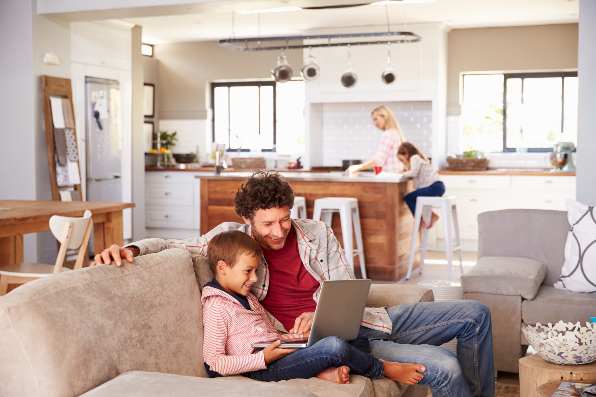 Adulte et enfant sur un canapé à la maison qui utilisent un ordinateur portable.