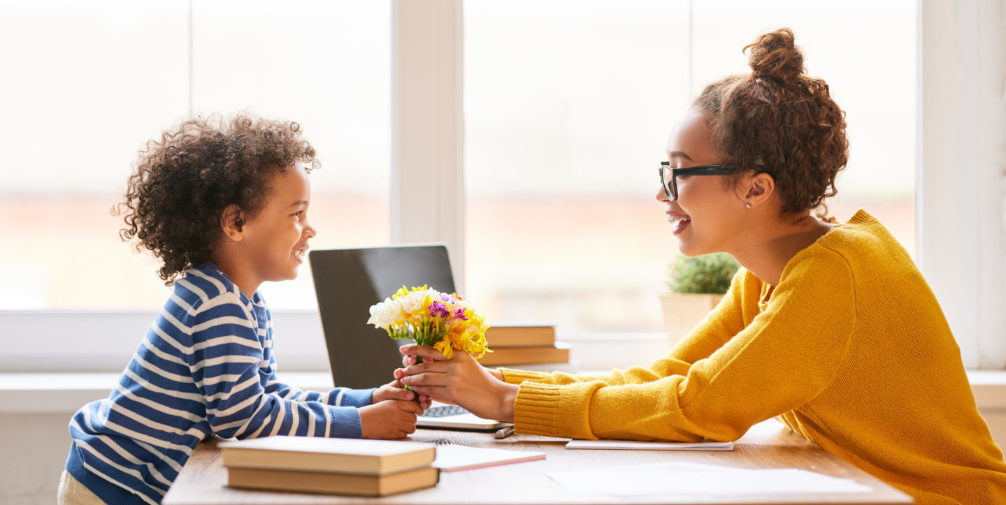 Enfant qui donne des fleurs à une personne adulte.