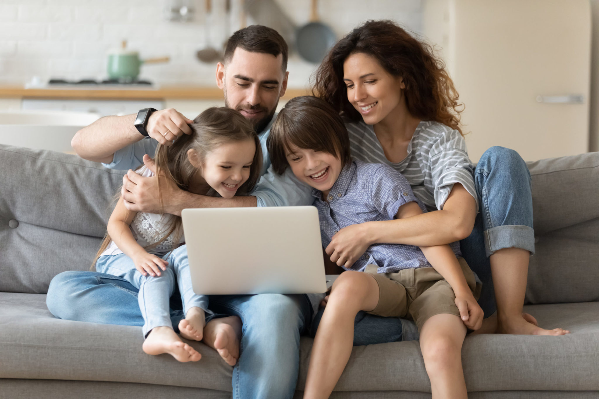 Famille heureuse qui utilise un ordinateur portable sur un canapé.