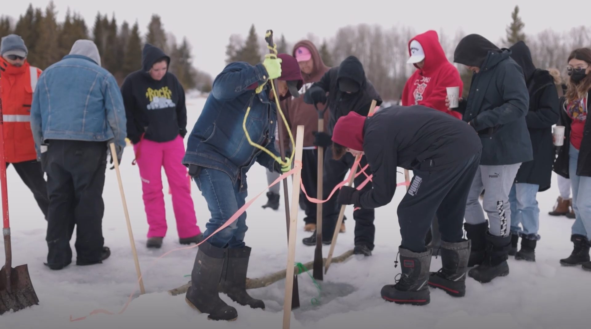 Group of children digging a hole on a frozen lake